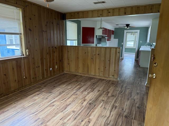511 Riverside Dr, Waycross, GA 31501 - kitchen featuring wood walls, wood finished floors, a ceiling fan, a peninsula, and decorative light fixtures