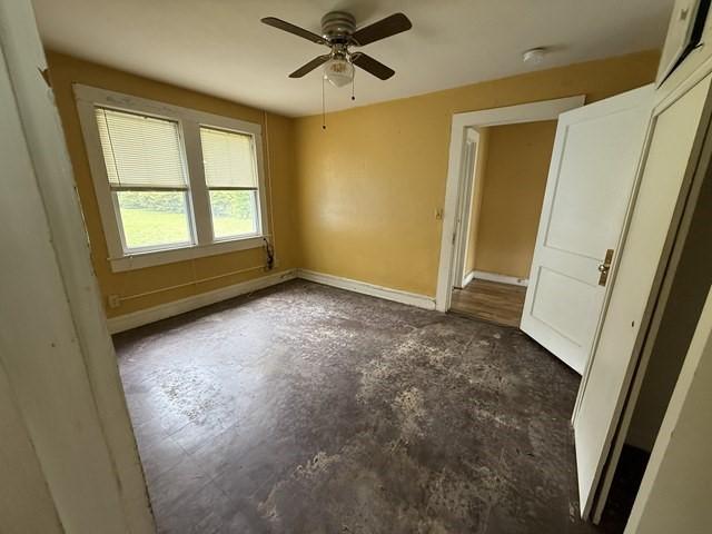 511 Riverside Dr, Waycross, GA 31501 - unfurnished bedroom with concrete floors, baseboards, and a ceiling fan