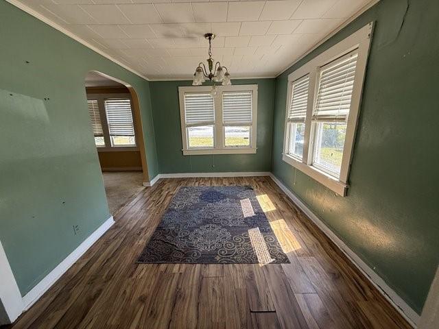 511 Riverside Dr, Waycross, GA 31501 - unfurnished dining area featuring ornamental molding, a chandelier, arched walkways, plenty of natural light, and wood finished floors