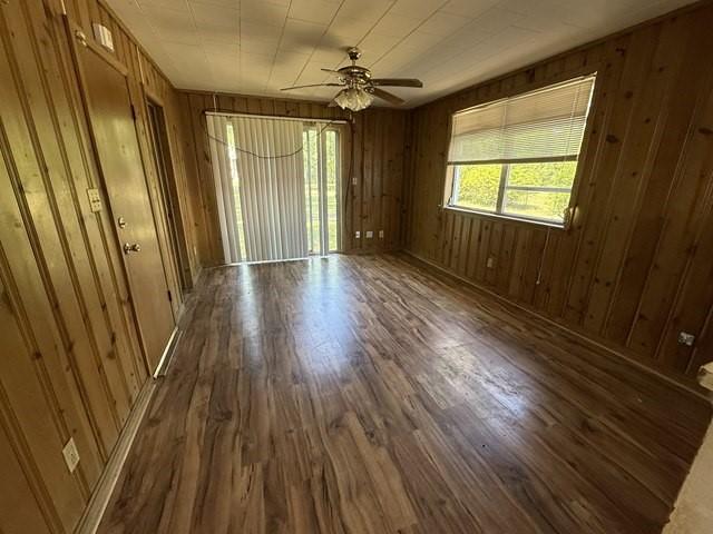 511 Riverside Dr, Waycross, GA 31501 - empty room featuring dark wood-type flooring, ceiling fan, and wood walls