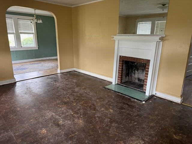 511 Riverside Dr, Waycross, GA 31501 - unfurnished living room with arched walkways, a fireplace, ornamental molding, healthy amount of natural light, and baseboards