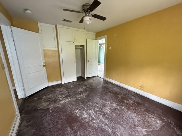 511 Riverside Dr, Waycross, GA 31501 - unfurnished bedroom with concrete floors, baseboards, a closet, and ceiling fan