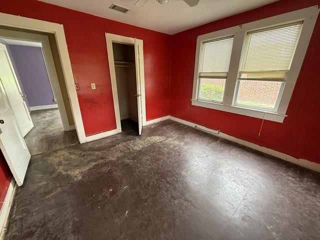 511 Riverside Dr, Waycross, GA 31501 - unfurnished bedroom featuring baseboards, a closet, concrete floors, and a ceiling fan
