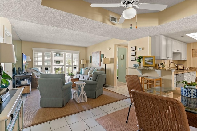 tiled living room with ceiling fan and a textured ceiling