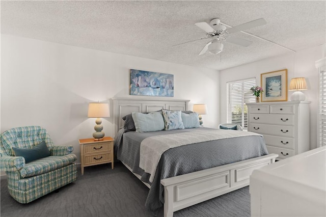 bedroom with ceiling fan, a textured ceiling, and dark colored carpet