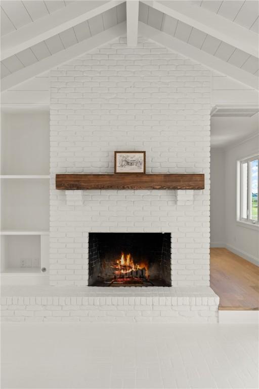 detailed view of a fireplace, beamed ceiling, wood finished floors, and baseboards