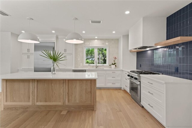 kitchen featuring high end stainless steel range oven, tasteful backsplash, light wood-style floors, light countertops, and a sink