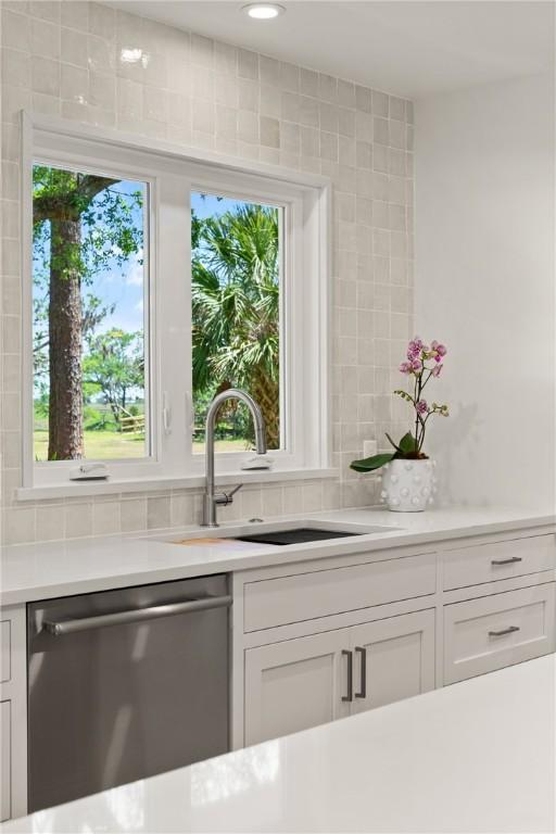 kitchen with dishwasher, a sink, light countertops, and white cabinets