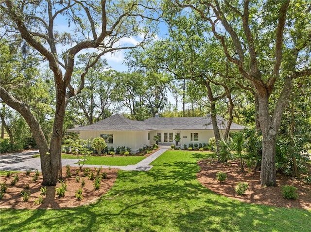 single story home with french doors and a front lawn