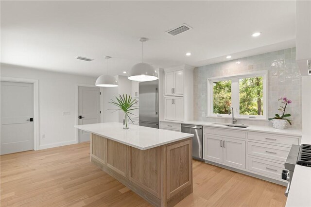 kitchen featuring a sink, stainless steel appliances, light wood-type flooring, light countertops, and recessed lighting