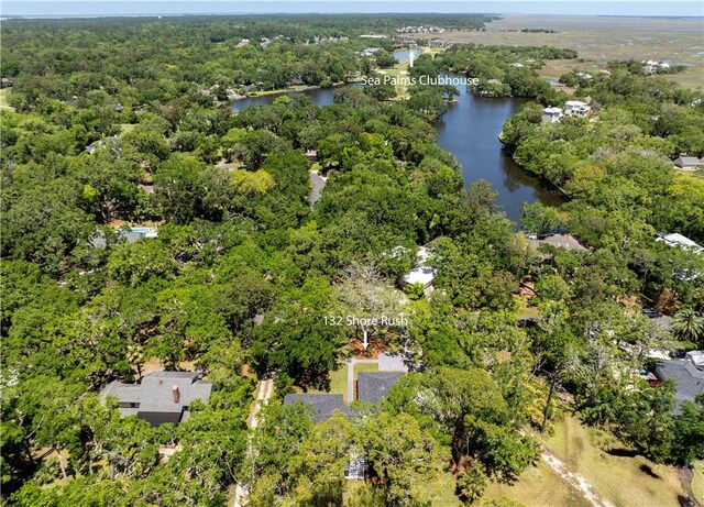 drone / aerial view of a nearby body of water and a heavily wooded area