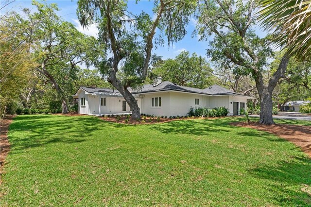rear view of house with a yard, a garage, and driveway