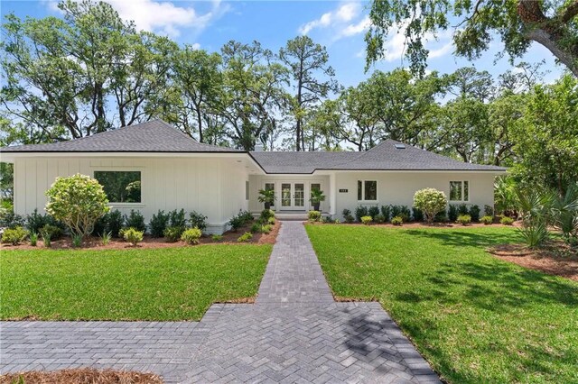 ranch-style house featuring french doors, a front lawn, and roof with shingles