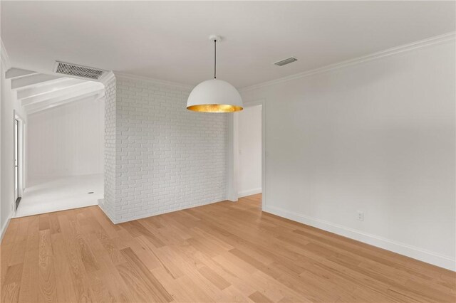 unfurnished dining area featuring wood finished floors, brick wall, ornamental molding, and baseboards