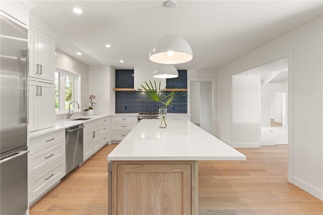 kitchen featuring appliances with stainless steel finishes, a sink, a center island, open shelves, and tasteful backsplash