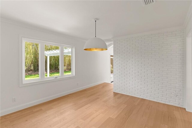 unfurnished dining area featuring crown molding, light wood-style floors, brick wall, and baseboards