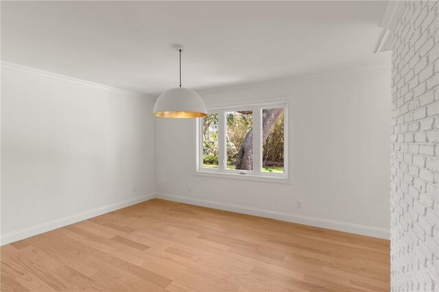 unfurnished dining area featuring light wood-type flooring, crown molding, and baseboards