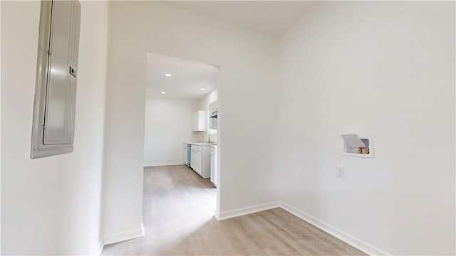 hallway featuring light wood-style flooring, a sink, baseboards, and recessed lighting