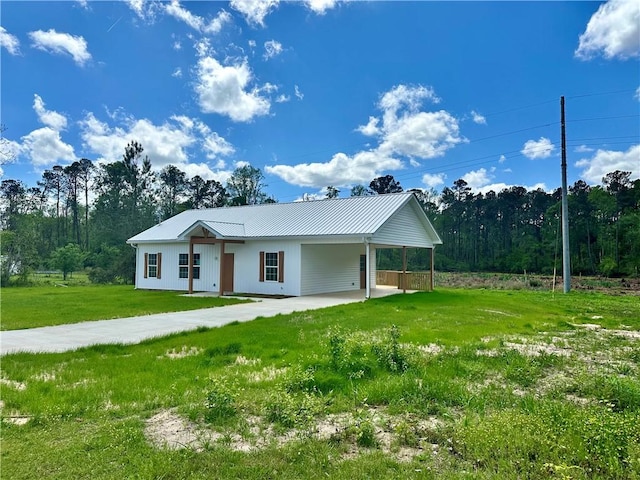 view of front of home featuring an attached carport, metal roof, a front lawn, and driveway