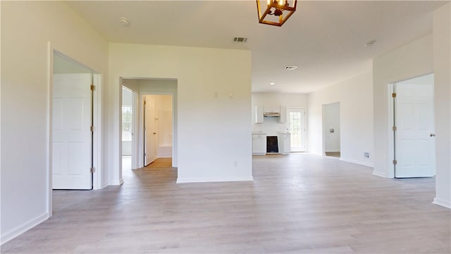 unfurnished living room with light wood-style flooring, baseboards, and visible vents