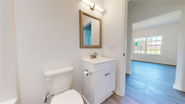 bathroom with baseboards, toilet, vanity, and wood finished floors
