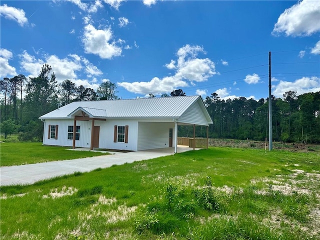 view of front of property with a front yard, concrete driveway, a carport, and metal roof