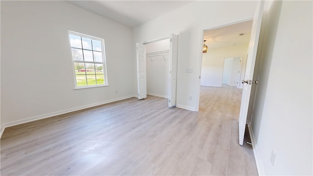 unfurnished bedroom with a closet, baseboards, and light wood-type flooring