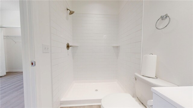 bathroom with toilet, wood finished floors, and a shower stall