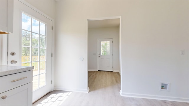 doorway featuring baseboards, a wealth of natural light, and light wood finished floors