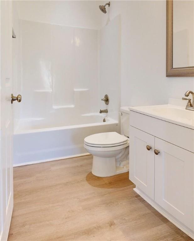 bathroom with toilet, wood finished floors, vanity, and shower / bath combination