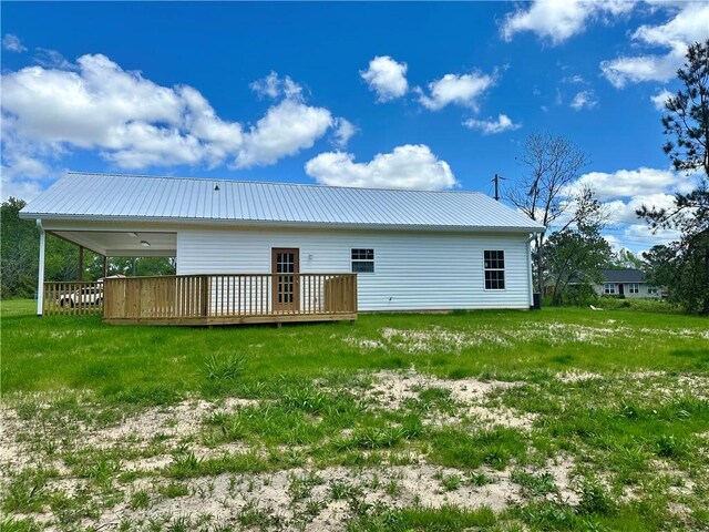 back of property featuring a lawn, metal roof, a wooden deck, and an attached carport