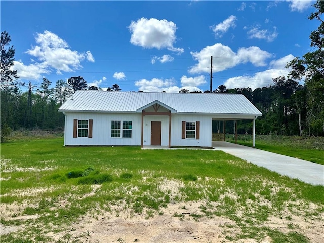 view of front facade with an attached carport, driveway, a front lawn, and metal roof