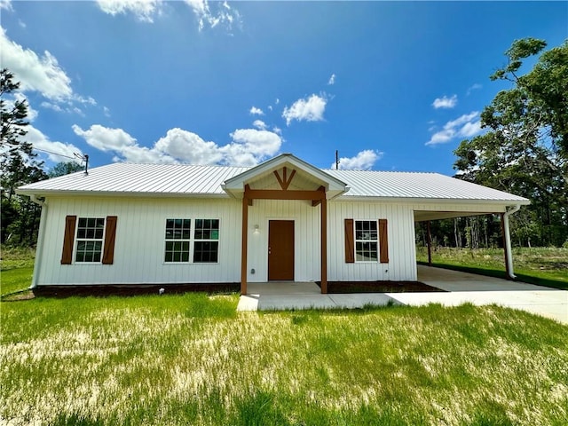 view of front facade featuring a front lawn, driveway, a carport, and metal roof