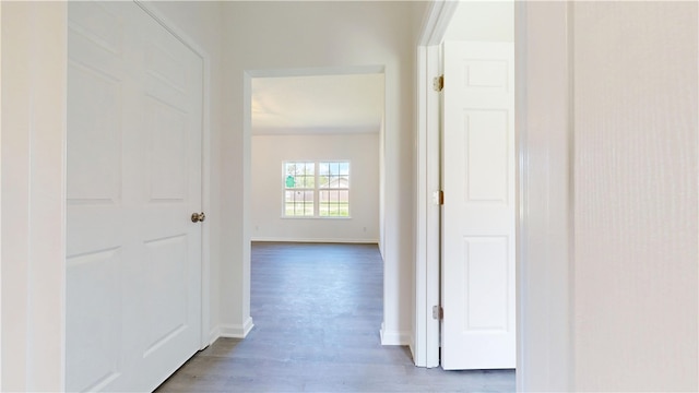 corridor featuring baseboards and wood finished floors