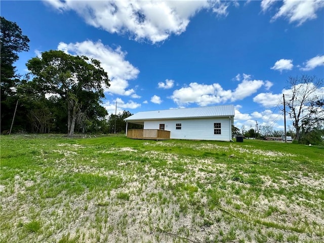 rear view of house featuring a lawn, metal roof, and a wooden deck