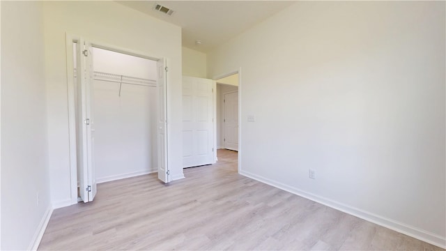 unfurnished bedroom with a closet, baseboards, light wood finished floors, and visible vents