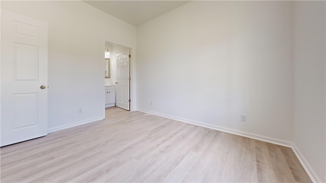 unfurnished bedroom featuring baseboards, ensuite bath, and light wood-style floors