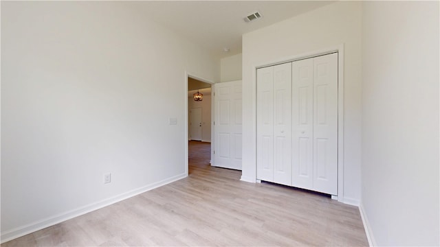 unfurnished bedroom with baseboards, light wood-style flooring, visible vents, and a closet
