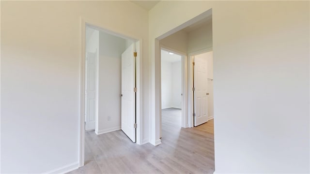 corridor with baseboards and light wood-type flooring