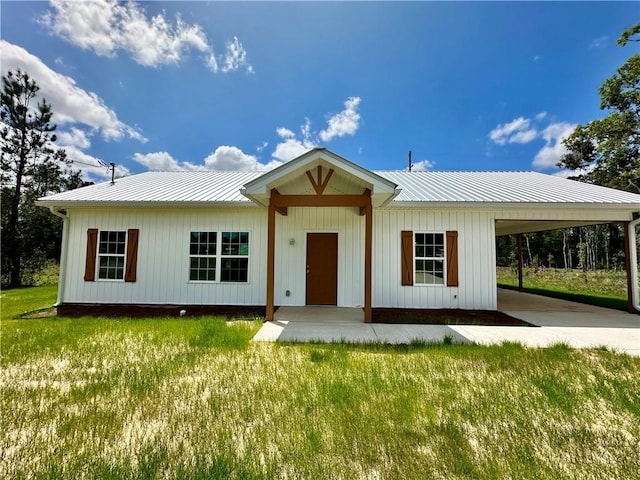 view of front of property with a front yard, driveway, a carport, and metal roof