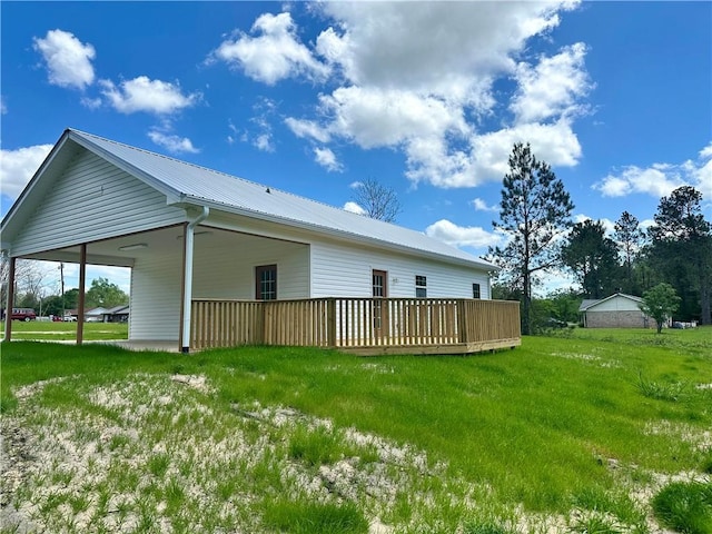 back of property with metal roof, a wooden deck, and a yard