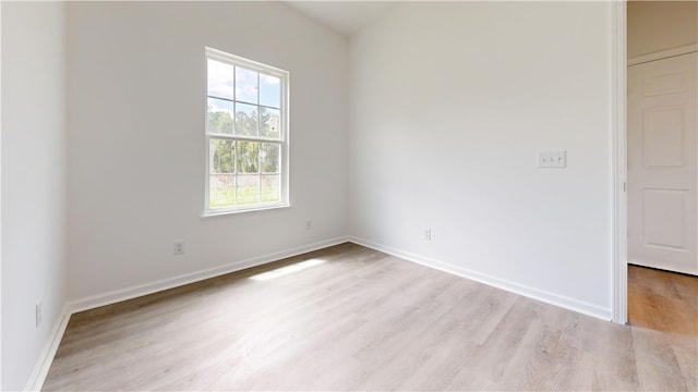 spare room featuring baseboards and light wood-style floors