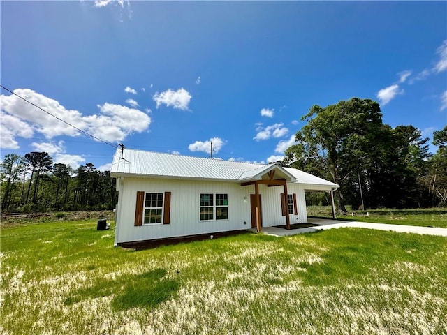view of front of property with driveway, a front yard, a carport, and metal roof