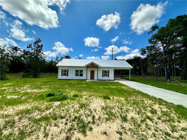 view of front of house featuring metal roof, driveway, a carport, and a front lawn