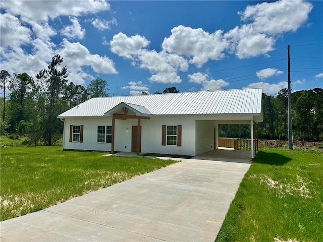 ranch-style home featuring an attached carport, a front yard, metal roof, and driveway