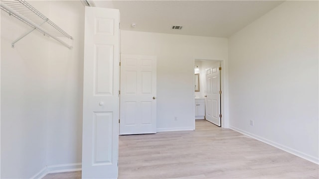 unfurnished bedroom featuring baseboards, visible vents, light wood-style floors, and ensuite bathroom