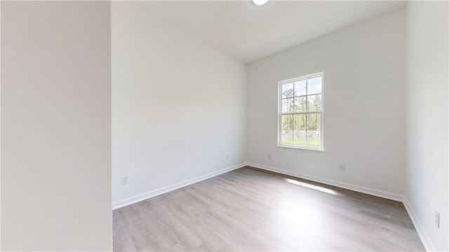 spare room featuring baseboards and wood finished floors