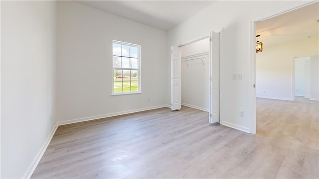 unfurnished bedroom featuring baseboards, light wood-type flooring, and a closet
