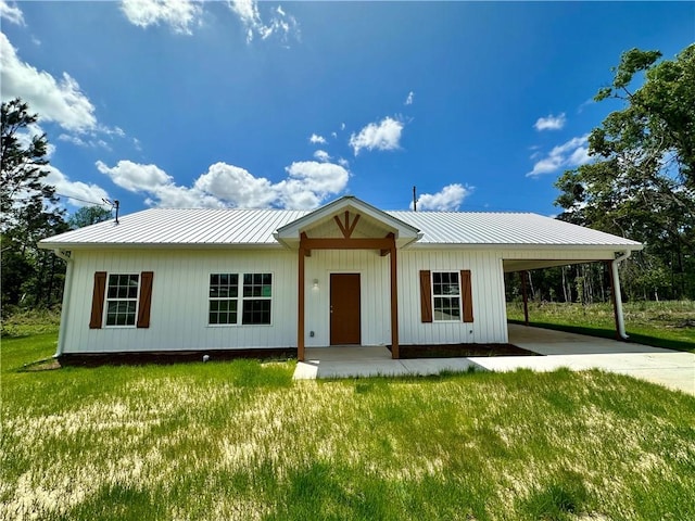 view of front facade featuring a front lawn, driveway, a carport, and metal roof