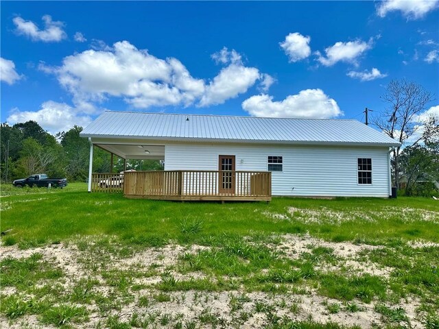 back of house with a yard, a carport, a deck, and metal roof
